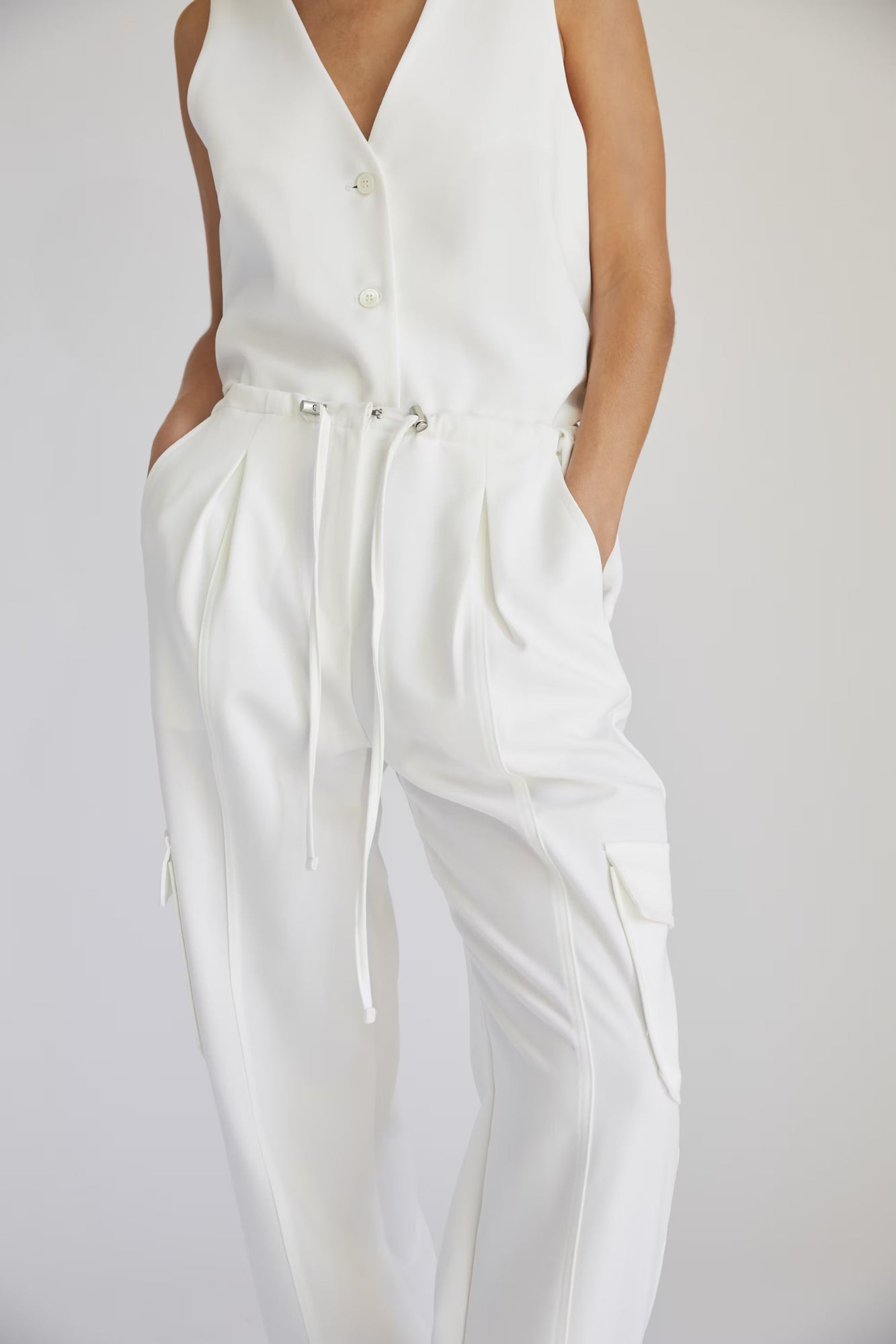 White sleeveless vest and white cargo pants on a plain background