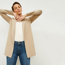 Front image of a woman standing wearing the Merritt jardigan in latte | Exclude