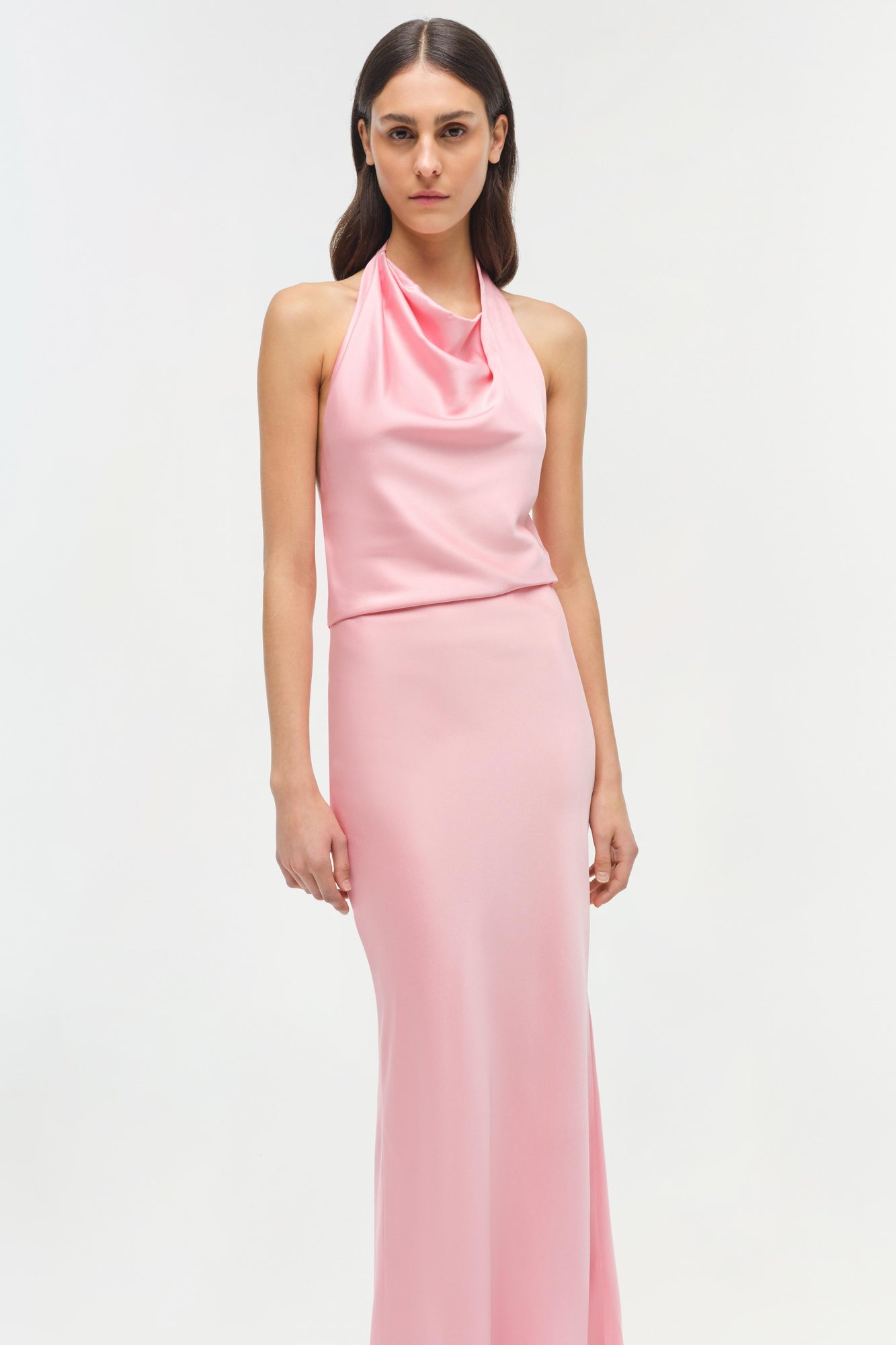 Woman wearing a pink satin halter gown with a draped neckline and fitted maxi skirt.