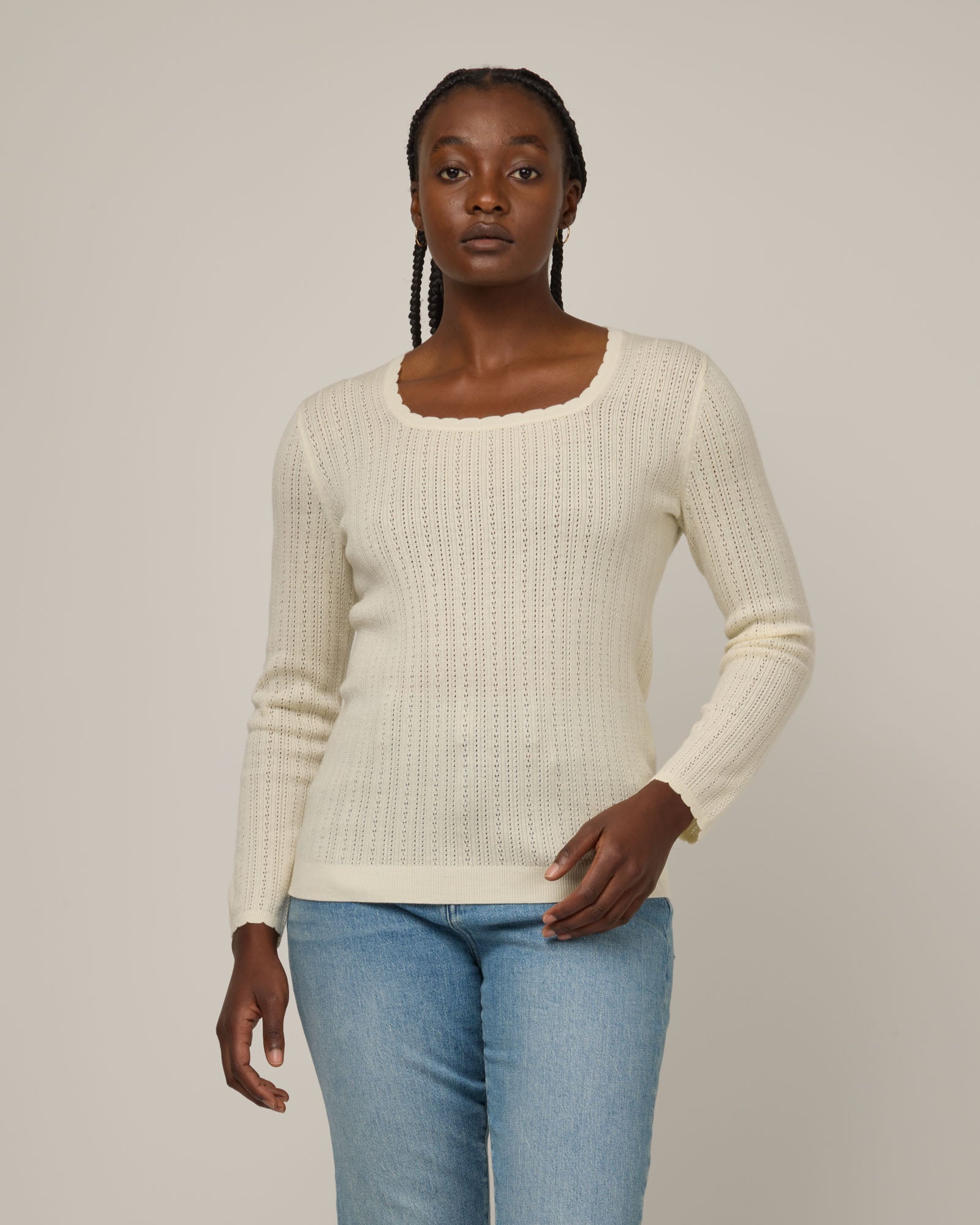 Model wearing Daisy Pointelle Sweater in Natural White, an off-white cream color. Daisy Pointelle Sweater is a merino wool long sleeve, square neck, regular fit sweater available in sizes XS-XXL.