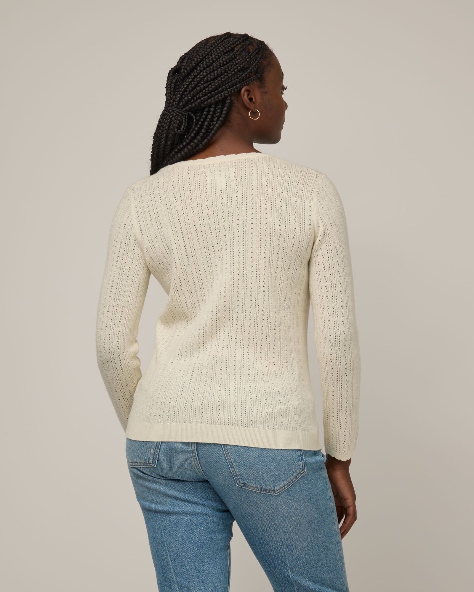 Model wearing Daisy Pointelle Sweater in Natural White, an off-white cream color. Daisy Pointelle Sweater is a merino wool long sleeve, square neck, regular fit sweater available in sizes XS-XXL.