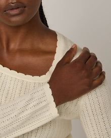 Model wearing Daisy Pointelle Sweater in Natural White, an off-white cream color. Daisy Pointelle Sweater is a merino wool long sleeve, square neck, regular fit sweater available in sizes XS-XXL.