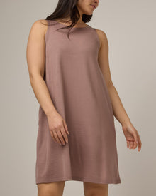 Model wearing Camellia Tank Dress in Ash Brown,  a soft brown color with purple undertones. Camellia Tank Dress is a merino wool sleeveless, crew neck, knee length swing dress with pockets available in sizes XS-3X Regular, XS-3X Long.