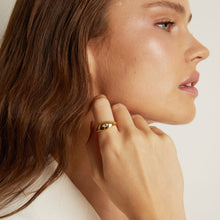 Close-up of a woman wearing a gold earring on a plain background