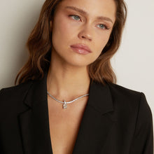 Model. Woman wearing a black blazer with a tennis necklace with a emerald gemstone pendant.
