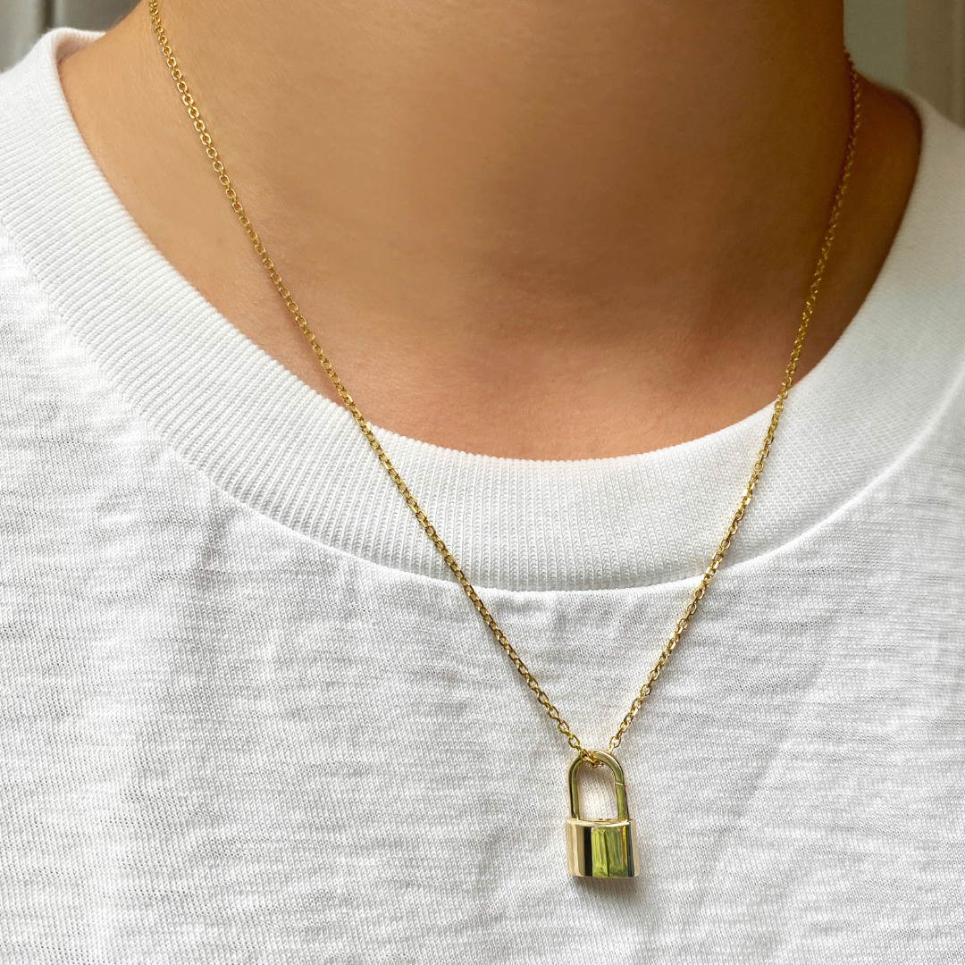 14k yellow gold padlock charm. Styled on a neck locked onto a diamond cut cable chain necklace.