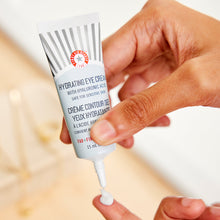 A woman dispensing a pea-sized amount of Hydrating Eye Cream onto fingertip. 