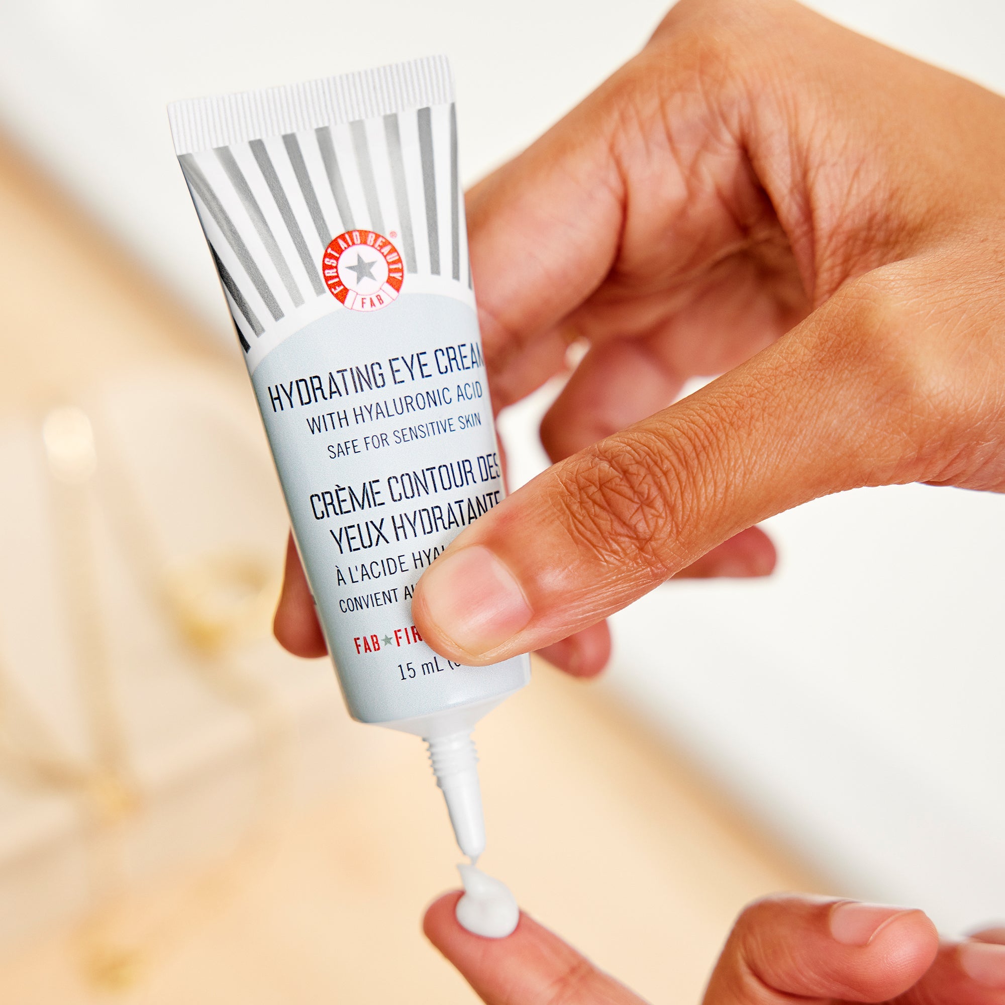 A woman dispensing a pea-sized amount of Hydrating Eye Cream onto fingertip. 