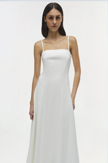 Woman wearing white sleeveless midi dress with square neckline and thin straps.