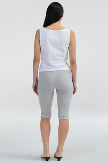 Woman wearing a white sleeveless top and gray shorts on a white background