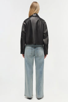 Black leather cropped jacket with collar shown on model wearing light blue jeans, rear view.