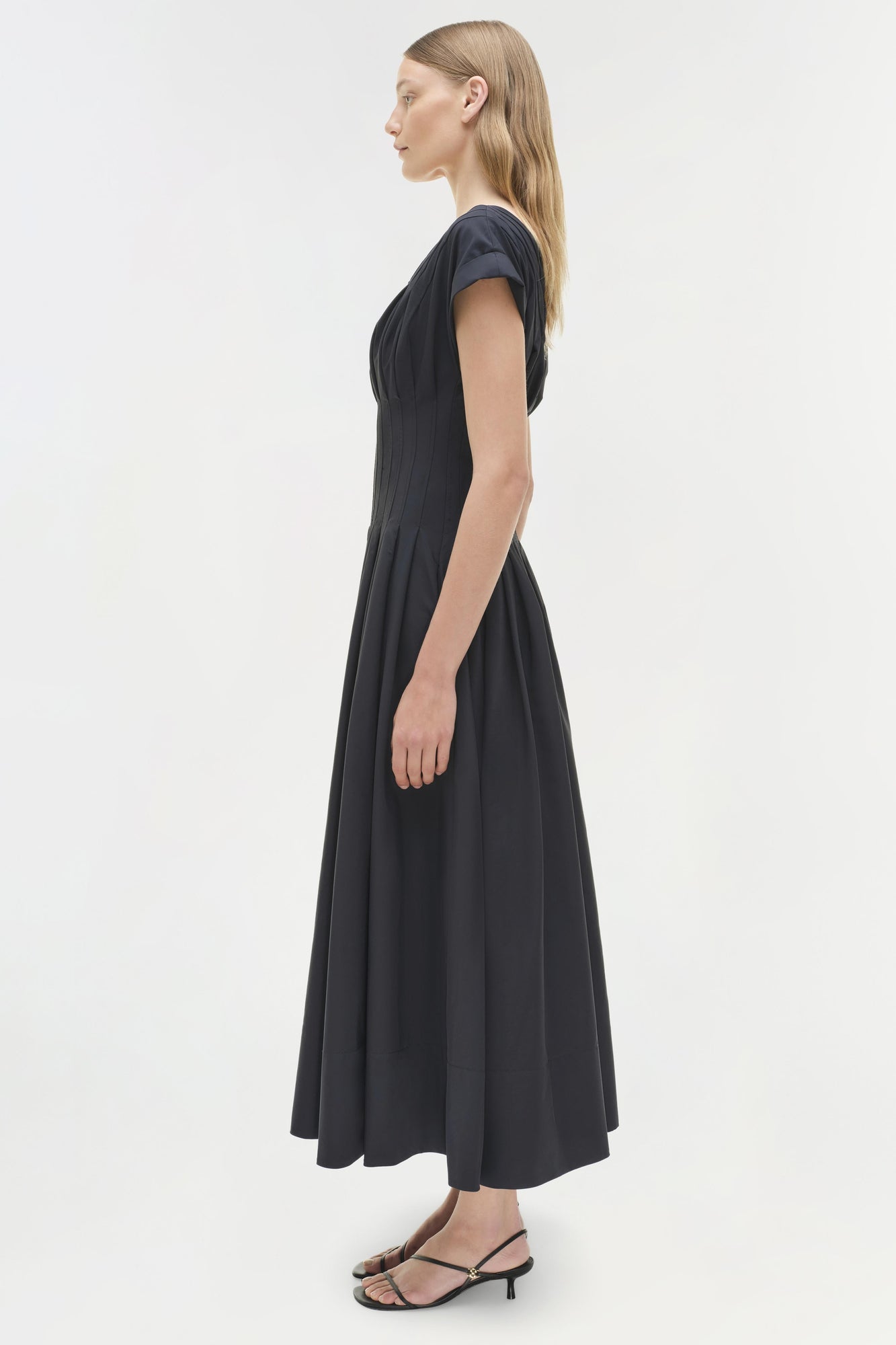 Black cotton midi dress with short sleeves and full skirt on model wearing black strappy heels.