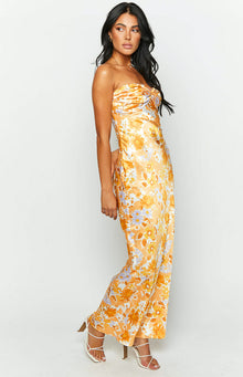 Side view of an orange floral strapless maxi dress with a twisted bust detail and a flowing skirt