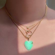 14k gold Demi Pavé Ripple Charm. Styled on a neck hanging from a diamond cut bead necklace layered with multiple chains and charms