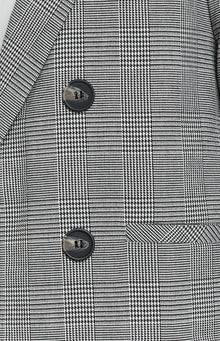 Black and white glen check blazer with two dark buttons, a notched lapel, and a flap pocket