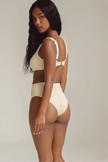 Cream ribbed bikini bottom with ruched detailing at back, worn with matching top.