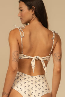 Cream bandeau bikini top with small dark floral print and tie-back straps shown from behind.