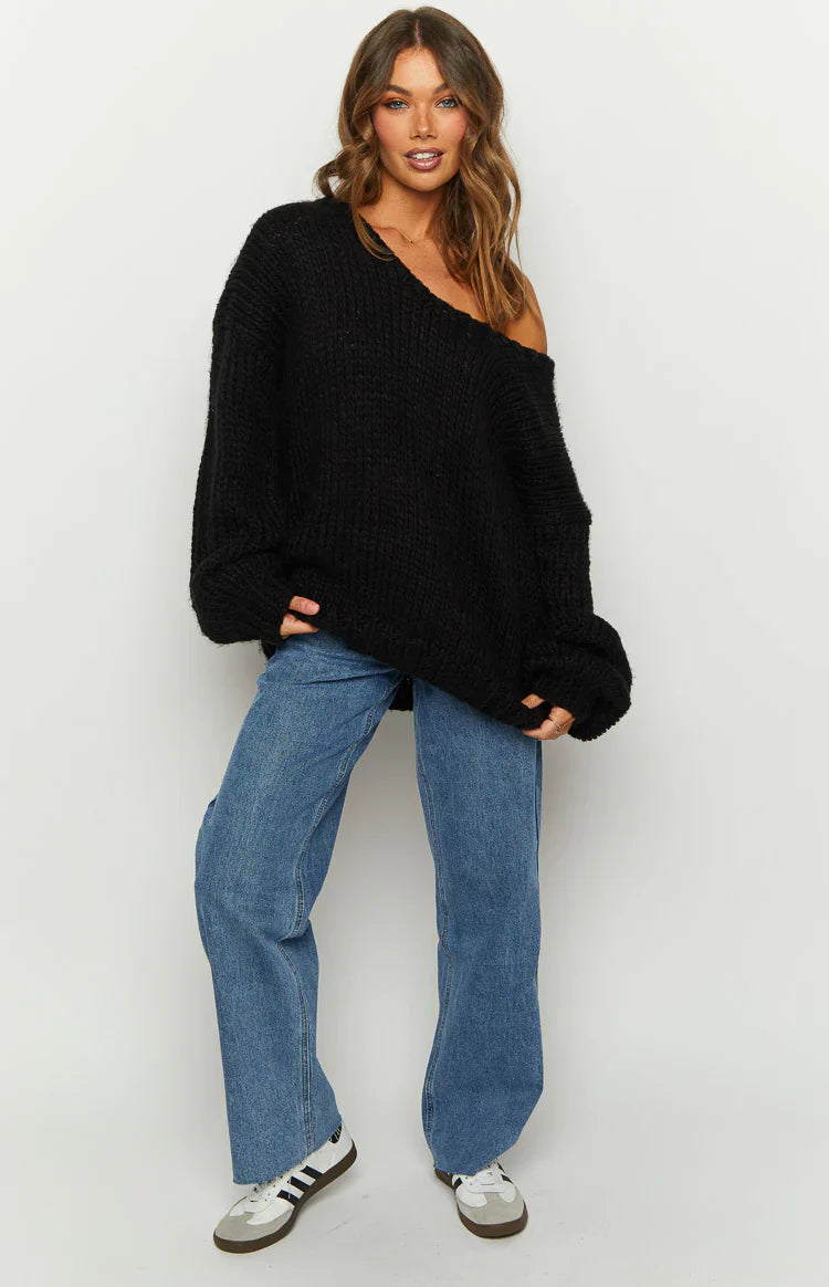 Black chunky knit sweater worn off one shoulder, showing the wide neckline and ribbed texture