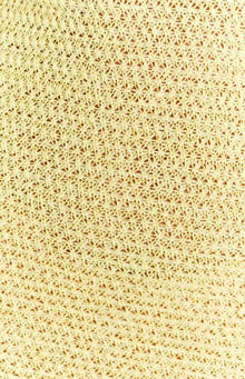 Close-up of the yellow crochet knit fabric with a geometric pattern of the maxi dress