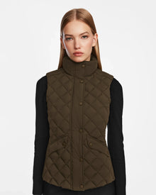 A woman with straight, light brown hair models the Rudsak MATILDA - L124504 Army dark olive womens vest over a black long-sleeve top against a plain white background.