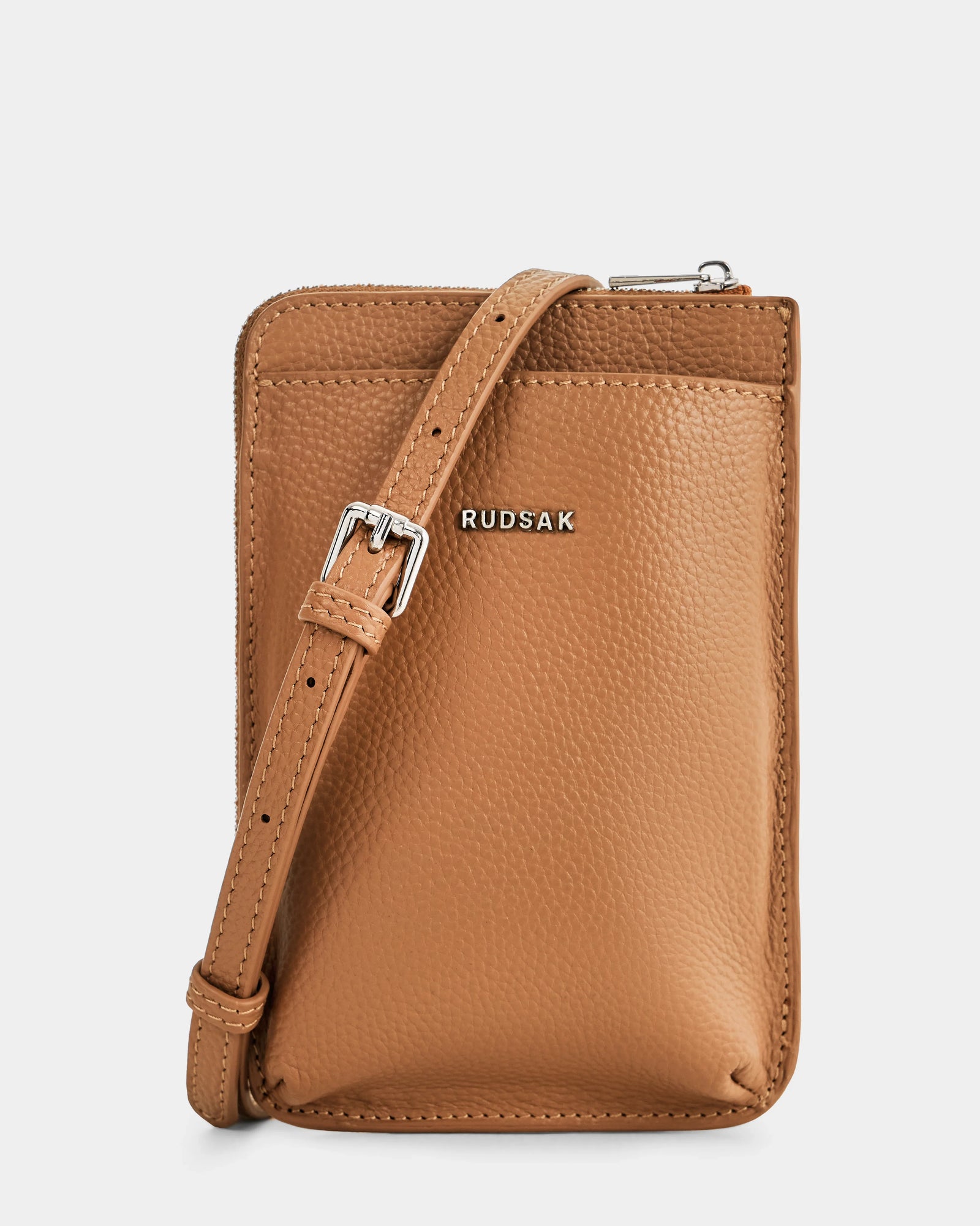 The CELYN - L325514 Taupe by Rudsak is a minimalist rectangular women’s leather crossbody in tan pebbled leather, featuring an adjustable strap with a silver buckle and RUDSAK in silver on the front—perfect for modern everyday city style.