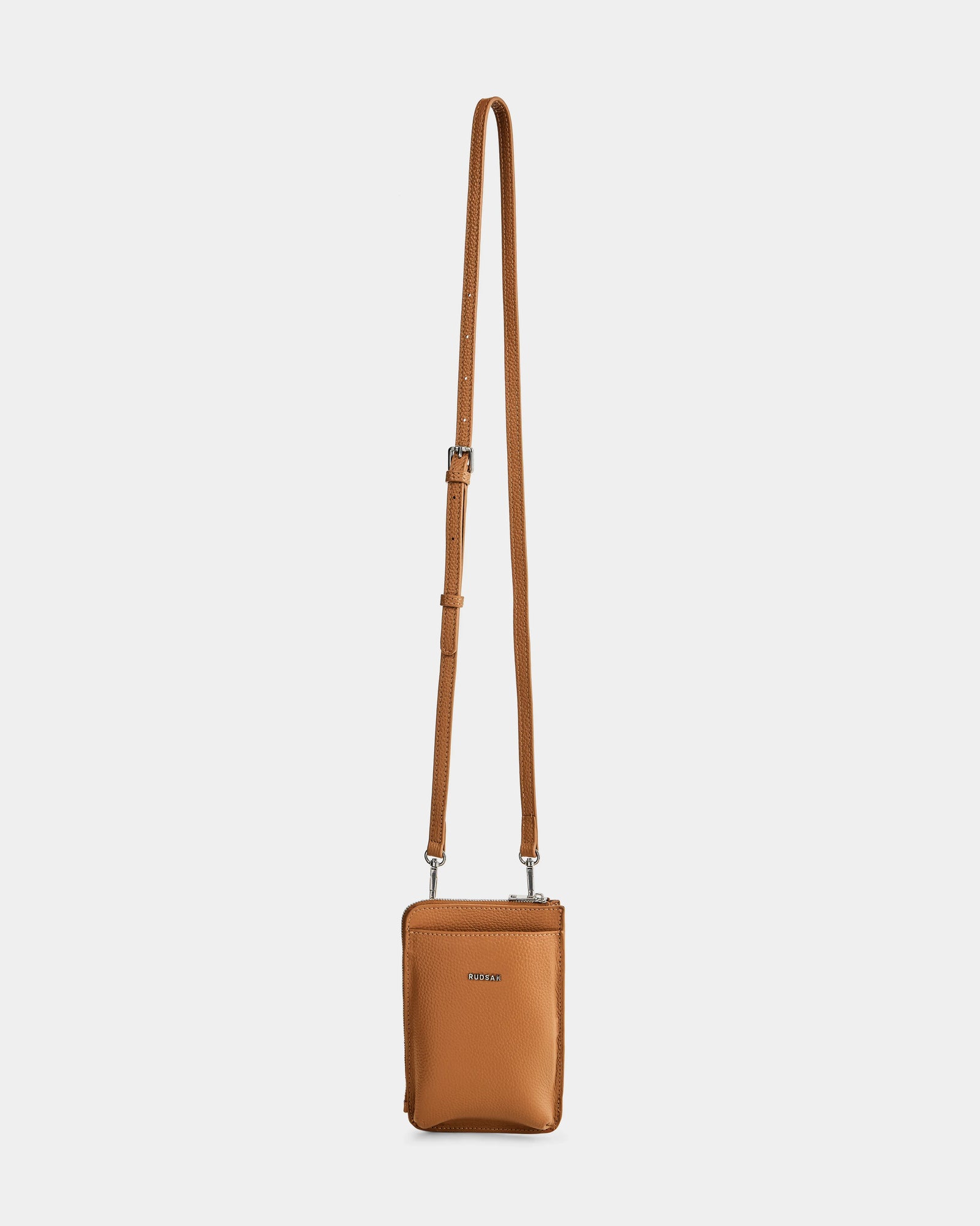 The Rudsak CELYN - L325514 Taupe is a small, rectangular women’s crossbody bag in tan pebbled leather with an adjustable long strap and a zippered top, shown against a plain white background.