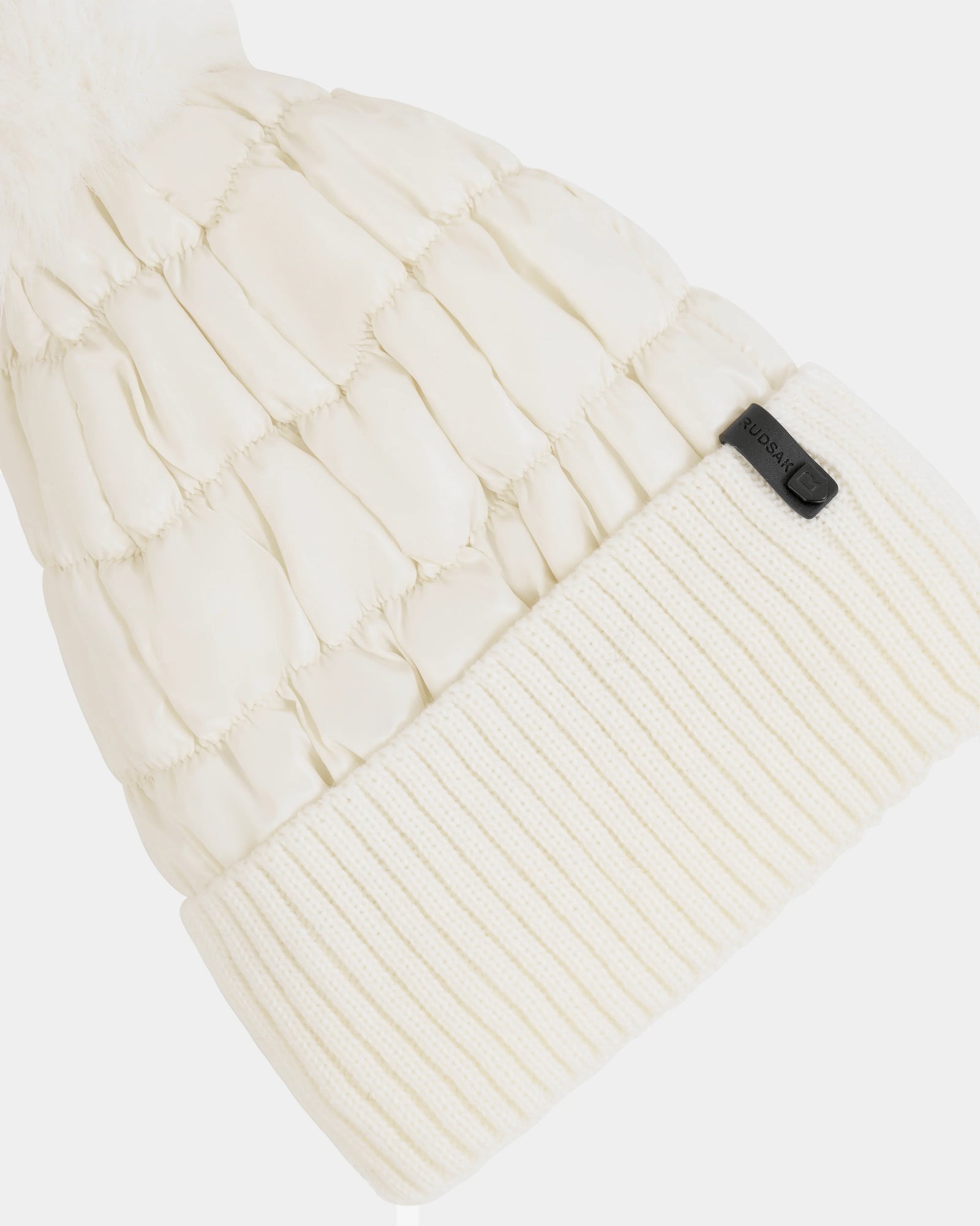 A close-up of the Rudsak LANYA - L423514 Iceland white quilted winter hat, featuring a ribbed knit fold-over cuff with a small black tag; its wool blend knit and quilted textures are clearly visible.