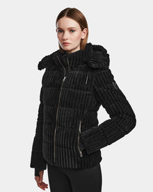 A woman with straight, shoulder-length hair wears the Rudsak MIRRY FF - L124507 Black women's short down puffer jacket, featuring a high collar and zippered pockets, against a plain light gray background.