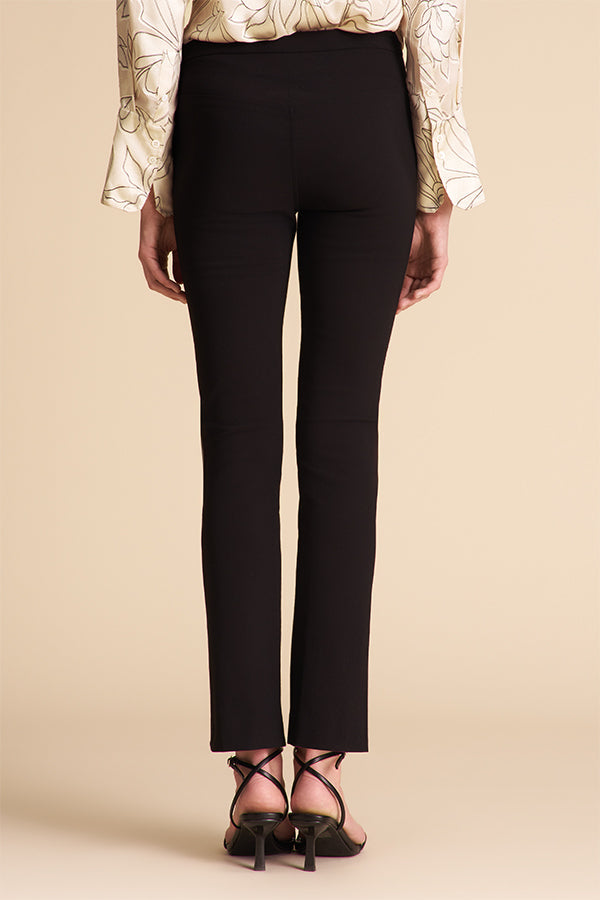 Person wearing black pants and a patterned top on a beige background | Exclude