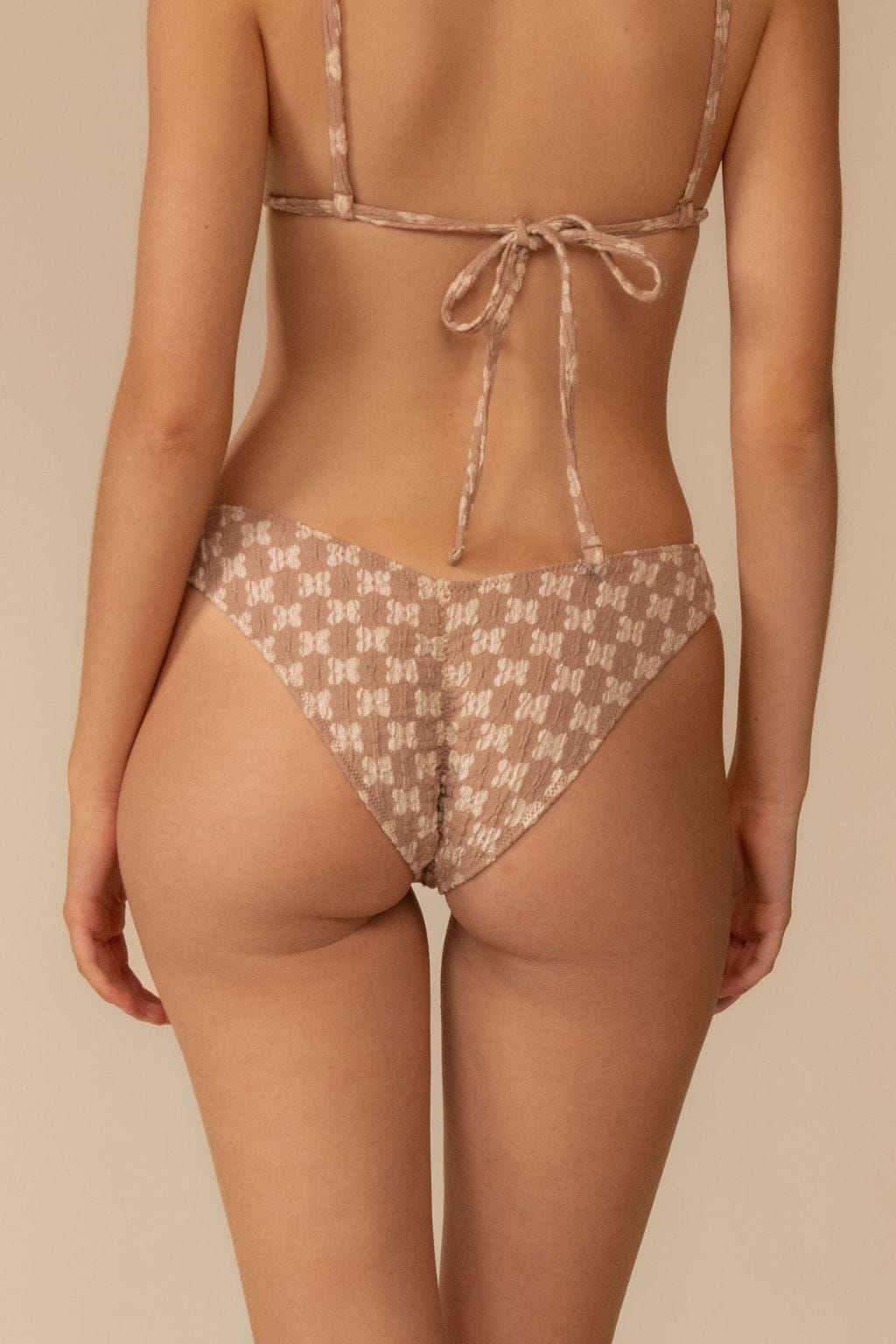 Beige lace bikini bottom with zig-zag stitch pattern and tie closure at back.