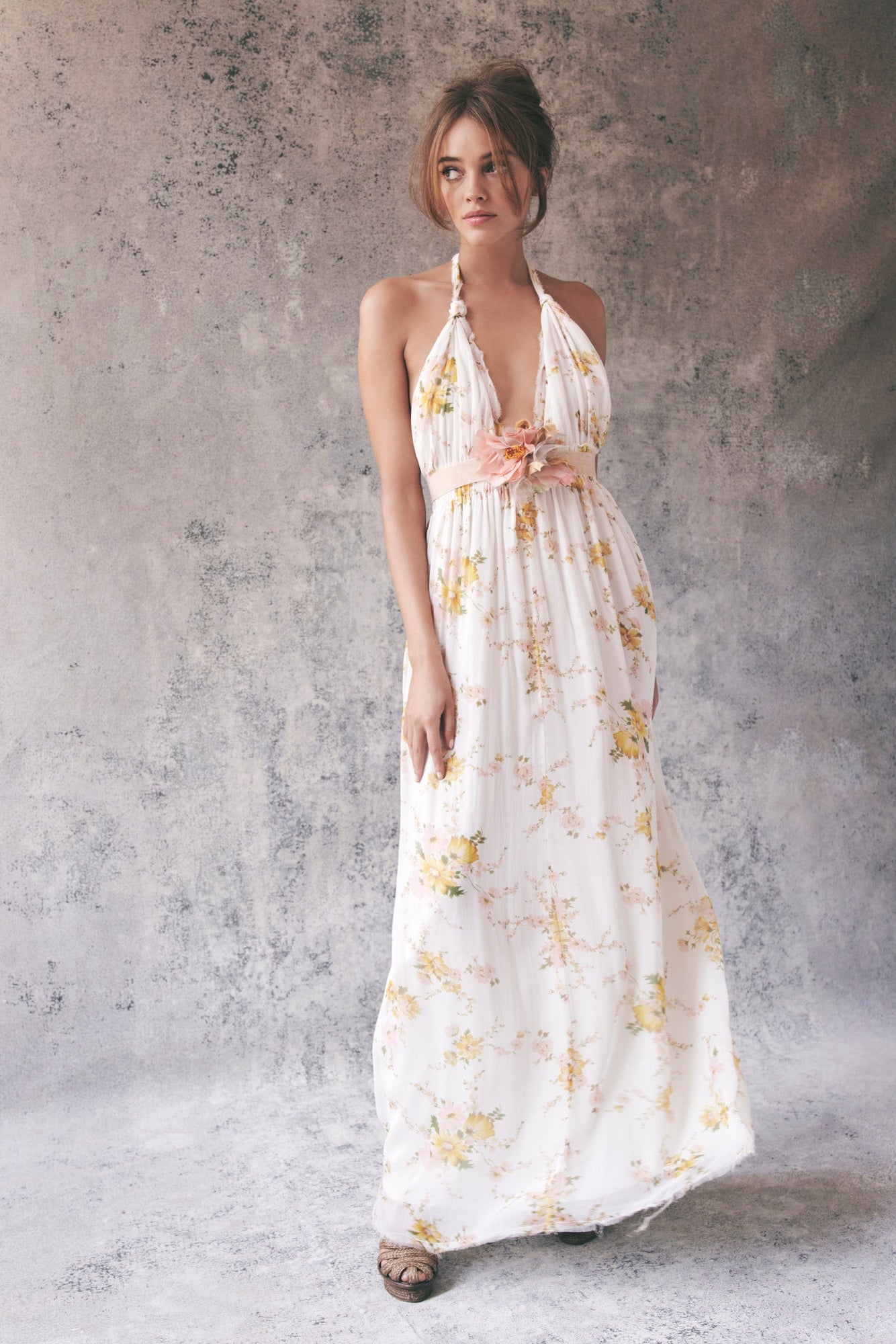 Model wearing white and yellow floral halter maxi dress