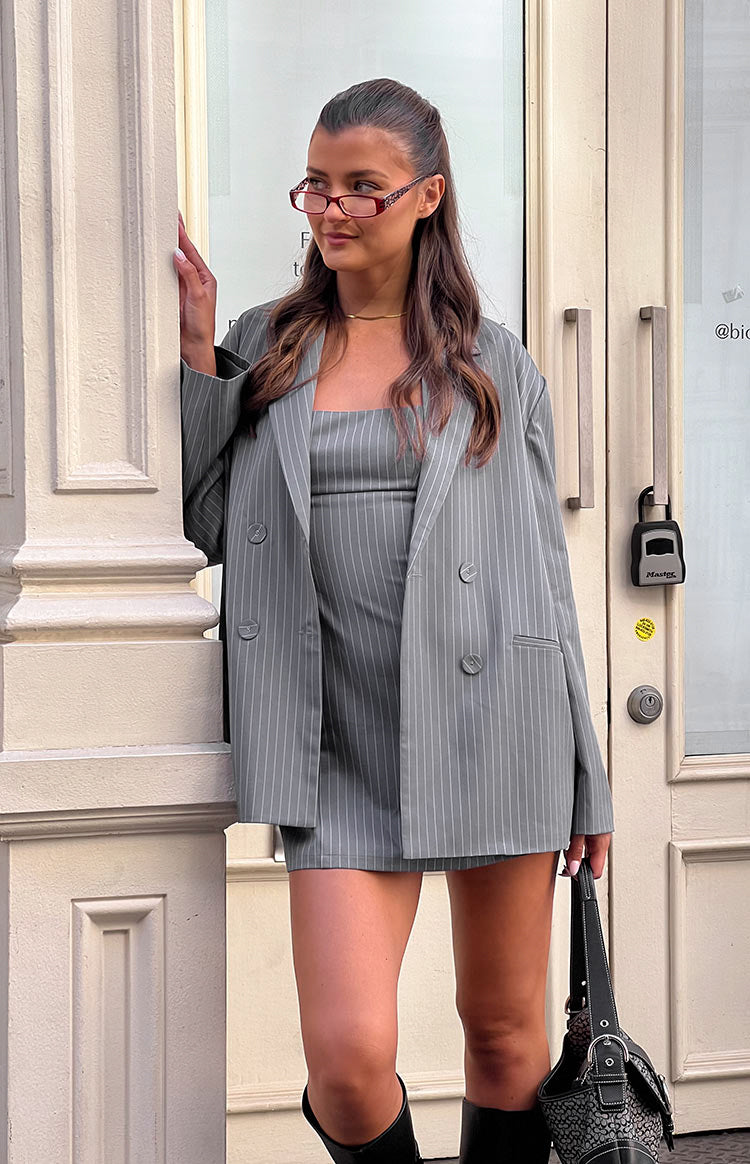 Oversized grey pinstriped blazer with double-breasted buttons, worn open for a relaxed fit