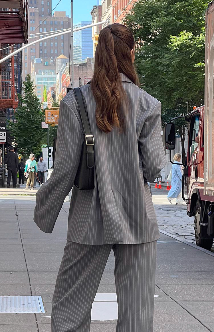 Grey pinstripe oversized blazer worn open over a matching pinstripe crop top and wide-leg pants