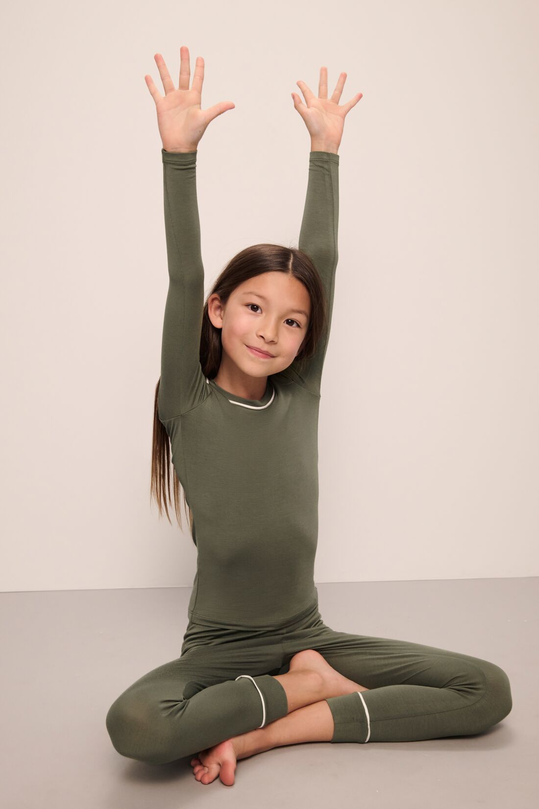 Model wears Kids TENCELâ„¢ Modal Unisex Long PJ Set in moss/ivory.