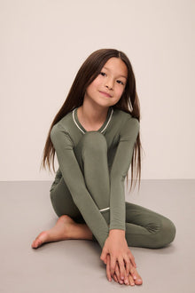 Model wears Kids TENCELâ„¢ Modal Unisex Long PJ Set in moss/ivory.