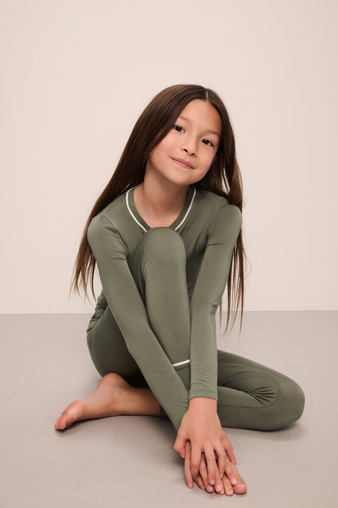 Model wears Kids TENCELâ„¢ Modal Unisex Long PJ Set in moss/ivory.