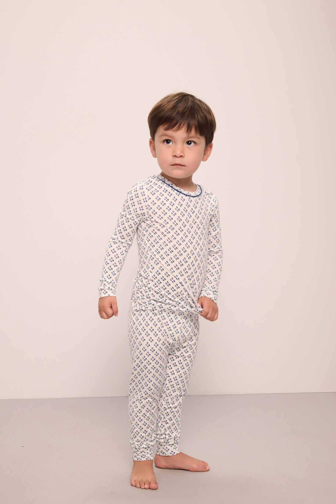 Model wears Kids Printed TENCEL Modal Unisex Long PJ Set in Petite Batik Ivory/Denim Blue.