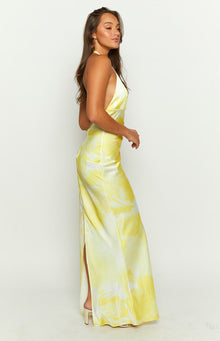 Side view of a yellow and white tie-dye halter neck maxi dress with a high side slit