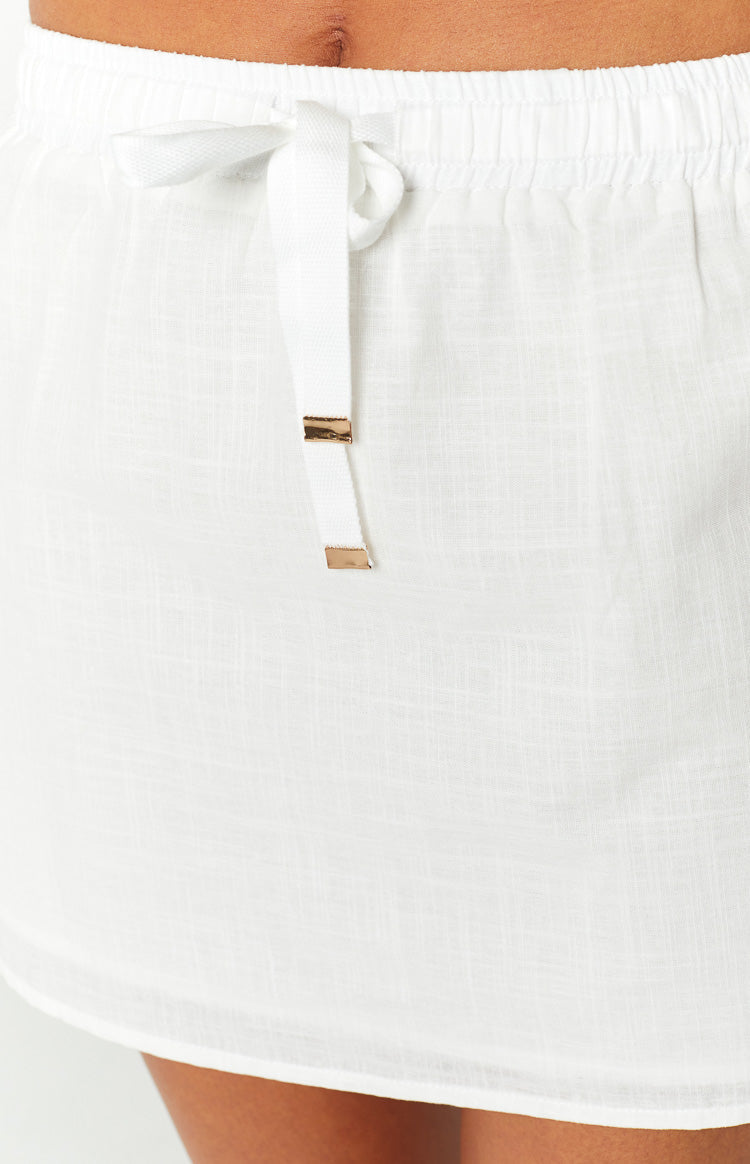 Close-up of the white mini skirt's elasticated waistband with a white drawstring tie and gold toggles