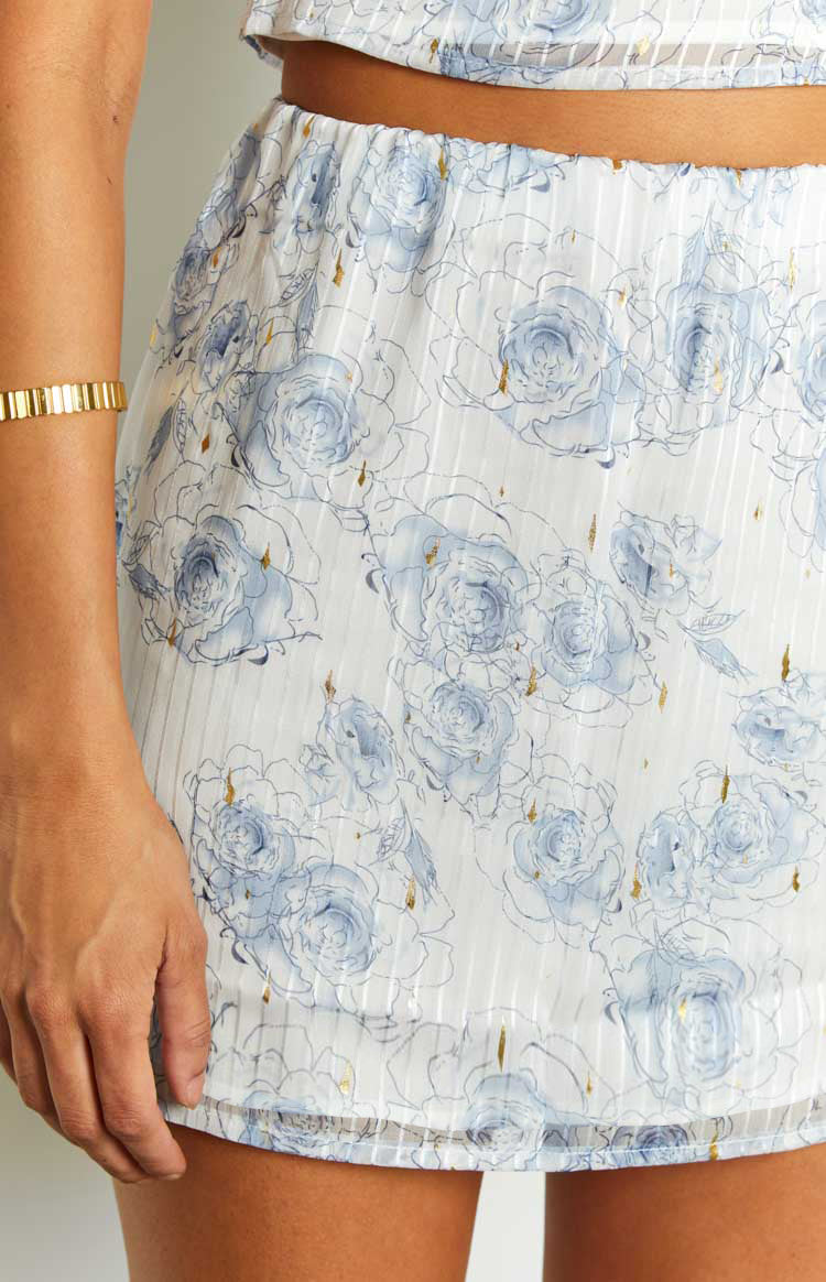 Close-up of the light blue mini skirt with blue rose print, gold flecks, and subtle vertical stripes