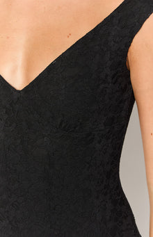 Close-up of the off-shoulder V-neckline and textured black floral lace of a fitted mini dress
