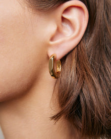 Model wearing huggie earring. 