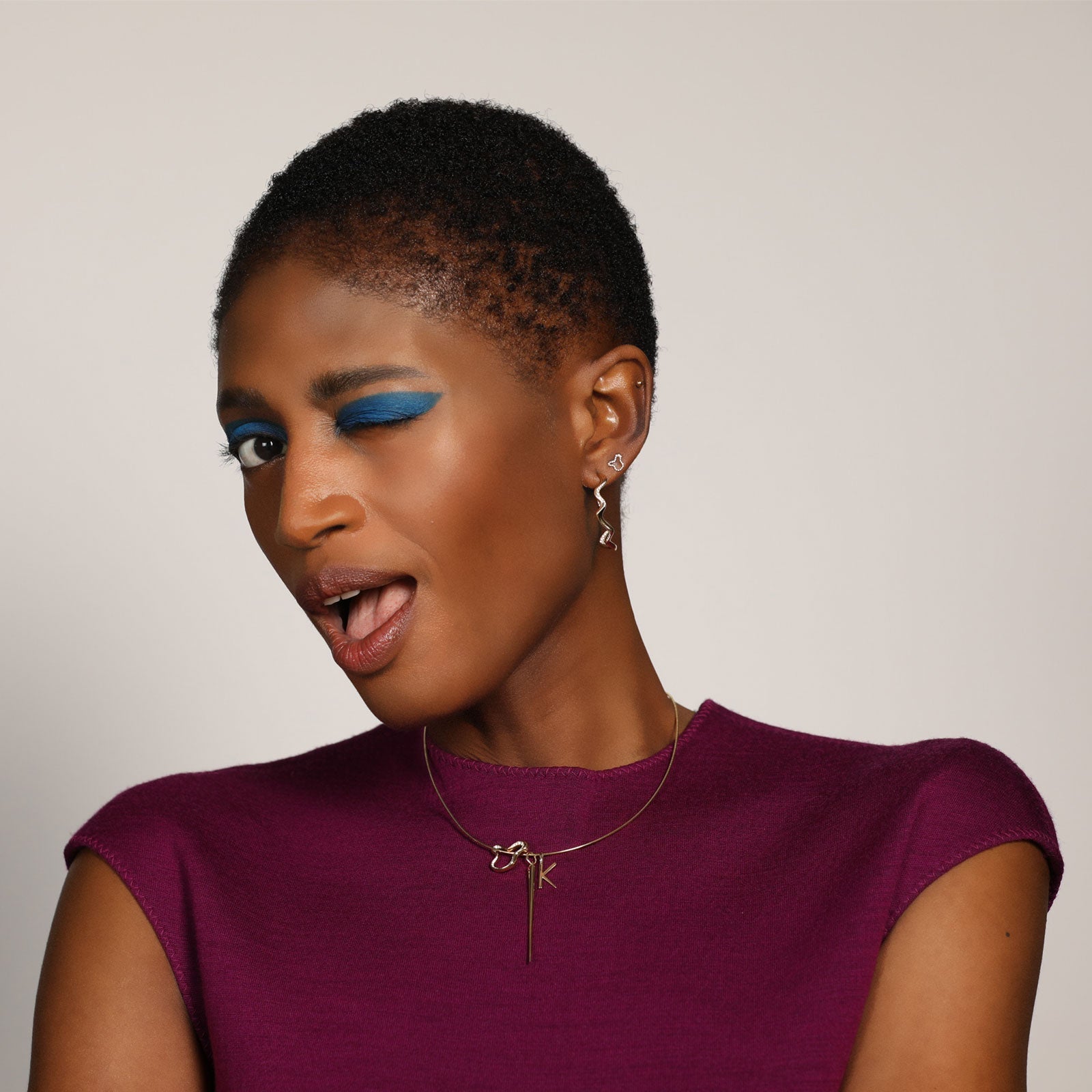 14k recycled gold Demi Pavé Ripple Charm. Hanging from a gold wire choker on model with letter K charm and Quill Spike Charm