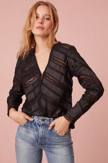 Long sleeve button down top with a v-neckline and diagonal laces for added texture detailing.