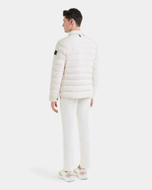 A man stands facing away, wearing the Rudsak AZIEL - M124521 Vanilla duck down jacket with white pants and sneakers against a plain white background.