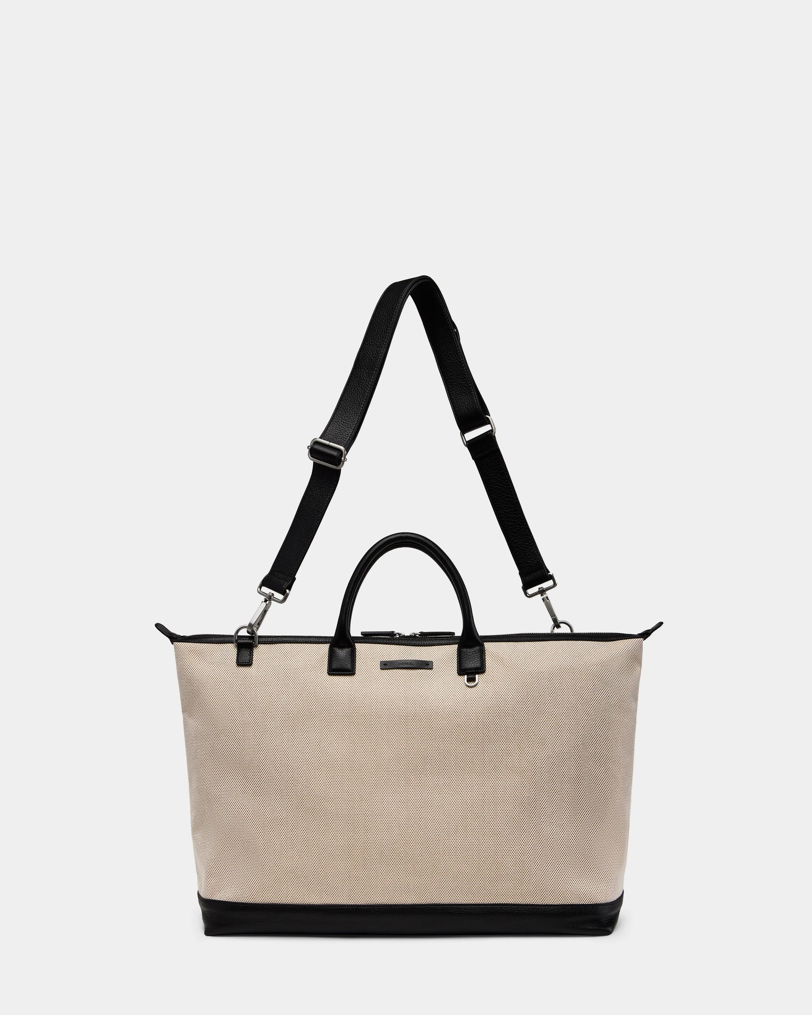 The Rudsak DUBLIN - 9324514 Vanilla is a unisex canvas leather tote with black handles, an adjustable shoulder strap, and sturdy black base—ideal as a weekender bag, shown against a plain white background.