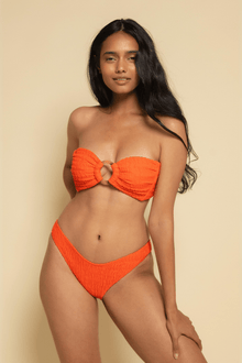 Tangerine bandeau bikini top with bow-tie center detail and textured fabric, shown on model with matching bottom.