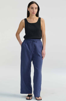Woman wearing a black tank top and blue pants on a white background