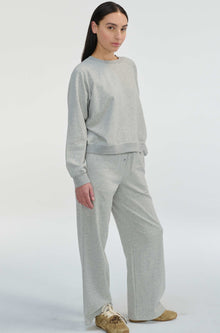 Woman wearing a gray sweatshirt and pants on a white background