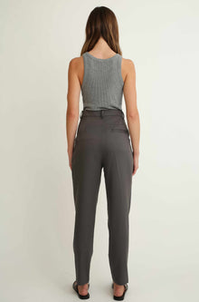 Woman wearing a gray sleeveless top and gray pants on a white background